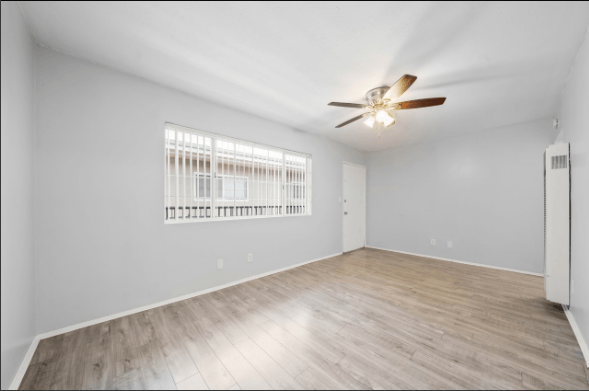 A room with a ceiling fan and a window with blinds.